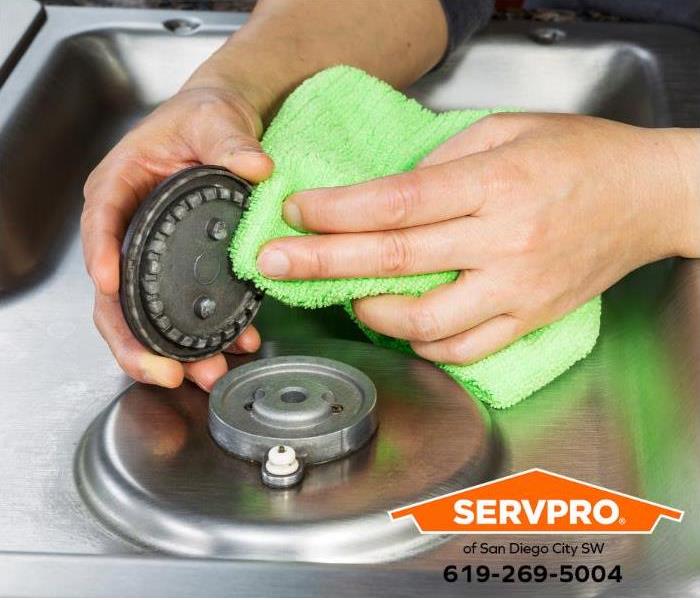 A person cleans the grease from a heating element to prevent a grease fire.